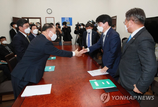 홍남기 경제부총리(왼쪽)와 더불어민주당 박완주 정책위의장이 30일 서울 여의도 국회 더불어민주당 원내대표실에서 예산협의를 위해 만나 악수하고 있다. <연합뉴스>